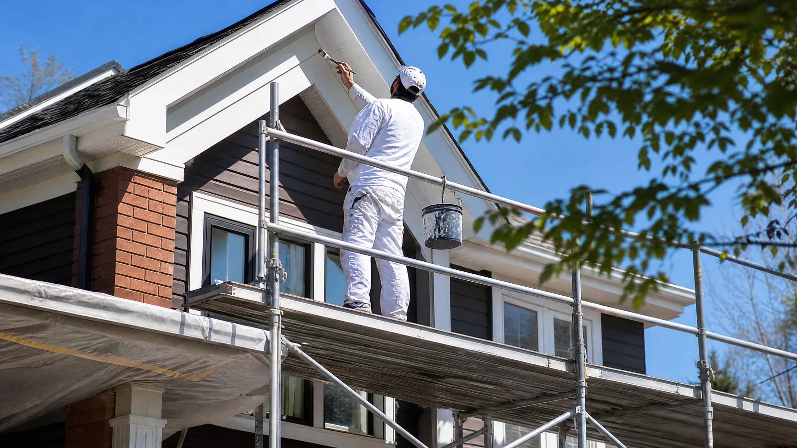 A painter cutting in the fascia of a two storey Toronto semi on a clear dry morning in late spring