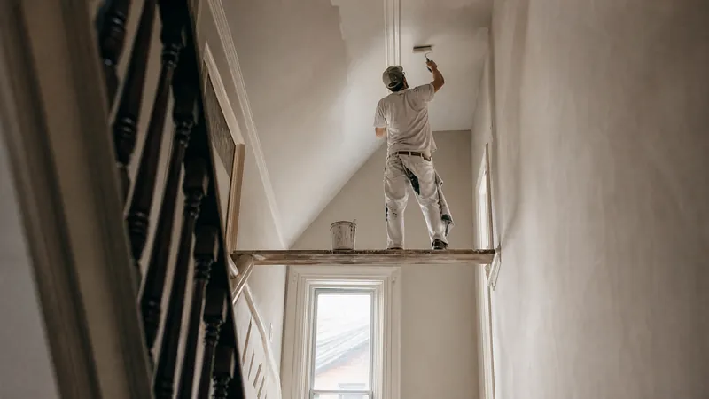 Painter rolling a fresh white finish across a living room ceiling in a Toronto home with the floor fully covered